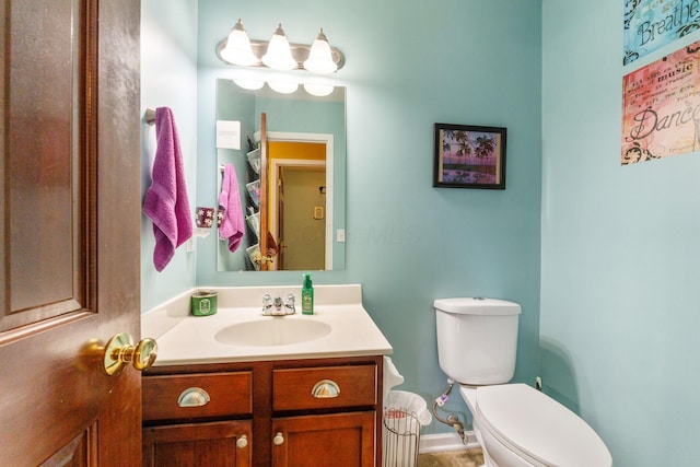 bathroom with baseboards, vanity, and toilet