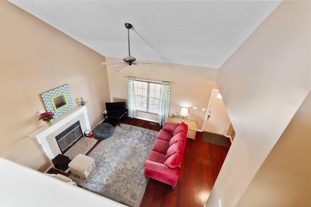 living room featuring lofted ceiling, a textured ceiling, wood finished floors, and a tile fireplace