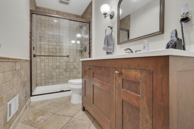 bathroom with toilet, a stall shower, vanity, and visible vents