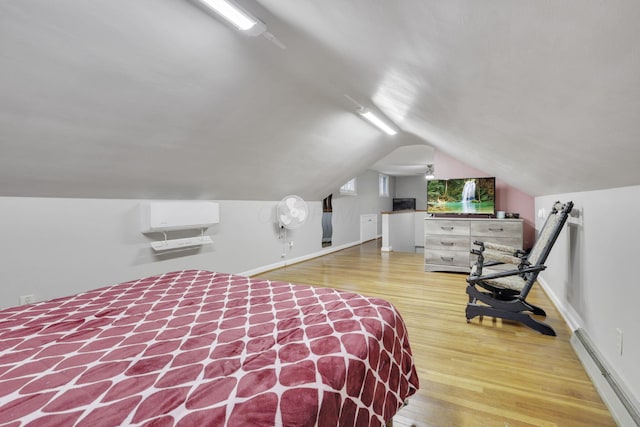 bedroom with vaulted ceiling, a baseboard radiator, wood finished floors, and baseboards