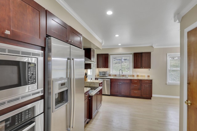 kitchen featuring ornamental molding, appliances with stainless steel finishes, a sink, and light wood-style floors