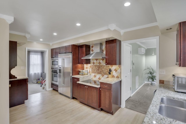 kitchen with decorative backsplash, wall chimney exhaust hood, light wood-style flooring, stainless steel appliances, and a sink