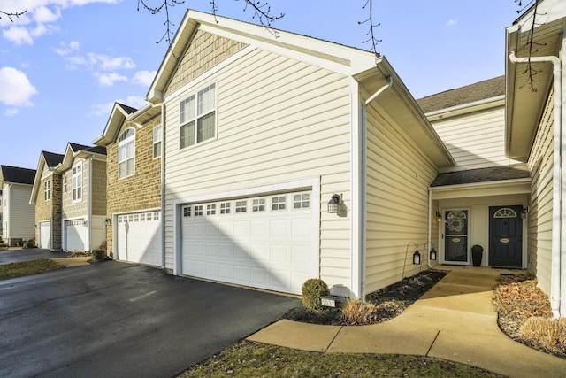 view of side of property with a garage, aphalt driveway, and a residential view