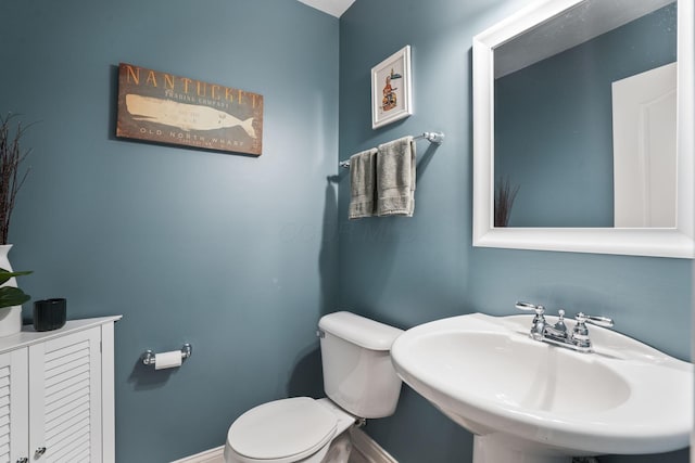 bathroom featuring baseboards, a sink, and toilet