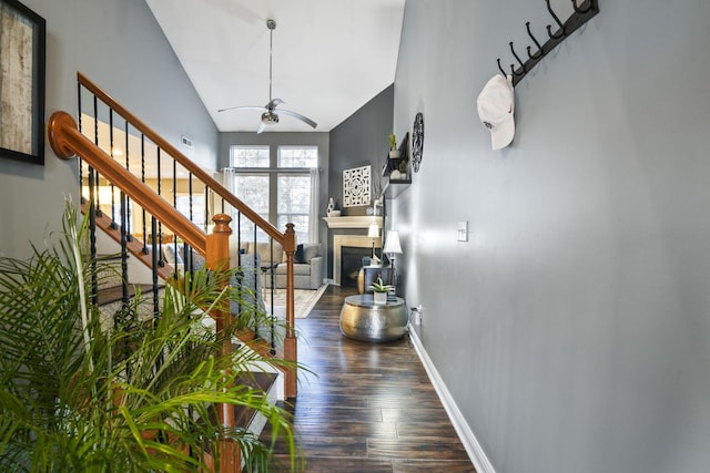 foyer featuring a fireplace, a ceiling fan, wood finished floors, baseboards, and stairs