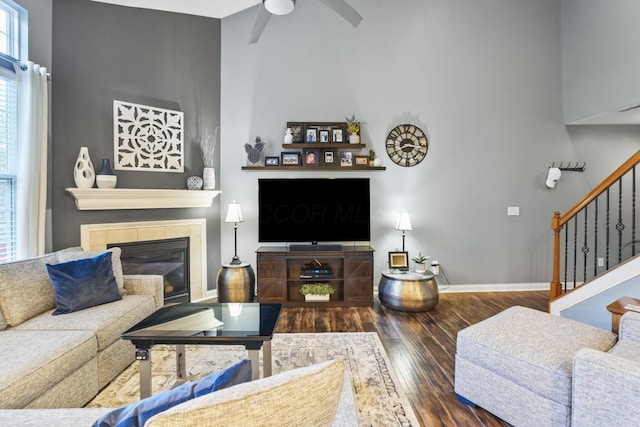 living room with baseboards, a ceiling fan, wood finished floors, stairs, and a fireplace