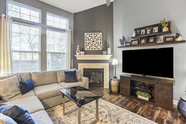 living area with baseboards, a tiled fireplace, and wood finished floors