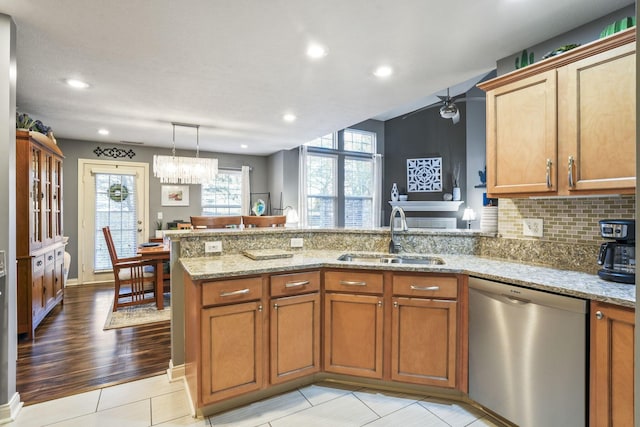 kitchen with a sink, a peninsula, brown cabinets, and stainless steel dishwasher