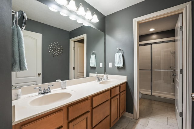 full bathroom with double vanity, a stall shower, a sink, and baseboards