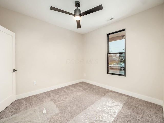 spare room featuring carpet floors, visible vents, baseboards, and ceiling fan