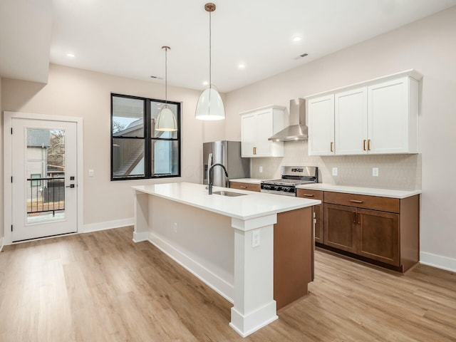 1093 Franklin Ave, Columbus, OH 43205 - kitchen with appliances with stainless steel finishes, a kitchen island with sink, light wood-style flooring, and wall chimney range hood