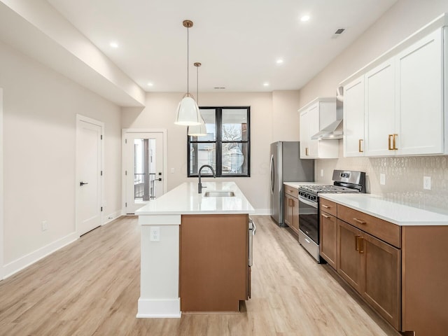 1093 Franklin Ave, Columbus, OH 43205 - kitchen with a center island with sink, backsplash, appliances with stainless steel finishes, a sink, and wall chimney range hood