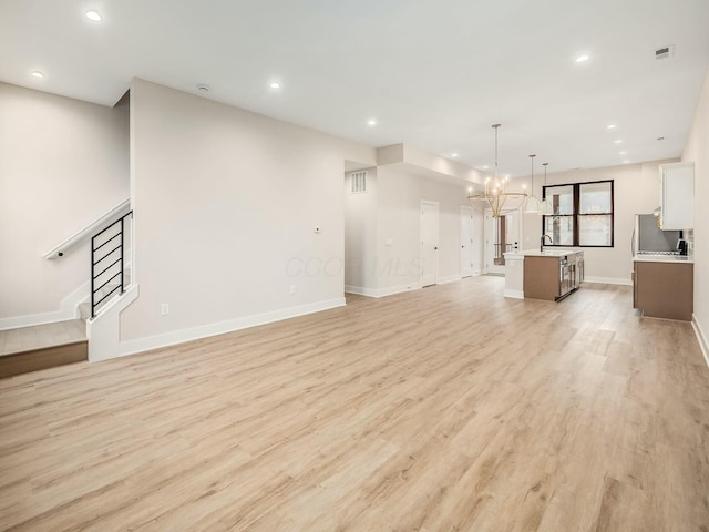 1093 Franklin Ave, Columbus, OH 43205 - unfurnished living room with recessed lighting, visible vents, stairway, light wood-style flooring, and a chandelier