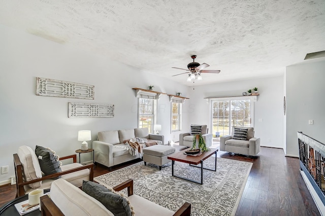 living room with ceiling fan, a textured ceiling, baseboards, and dark wood-type flooring