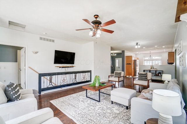 living area featuring ceiling fan with notable chandelier, dark wood-type flooring, and visible vents