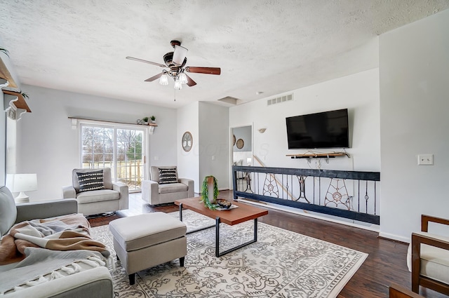 living area featuring visible vents, ceiling fan, a textured ceiling, wood finished floors, and baseboards