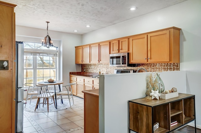 kitchen with pendant lighting, light tile patterned floors, stainless steel appliances, tasteful backsplash, and a textured ceiling