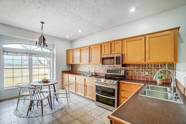 kitchen with a sink, appliances with stainless steel finishes, decorative backsplash, dark countertops, and plenty of natural light