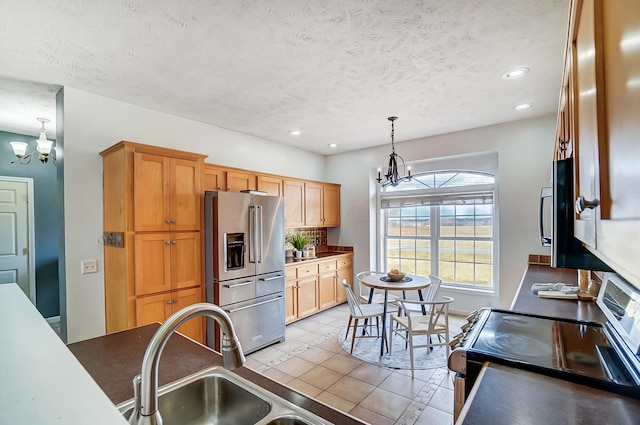 kitchen with a chandelier, a textured ceiling, a sink, hanging light fixtures, and appliances with stainless steel finishes