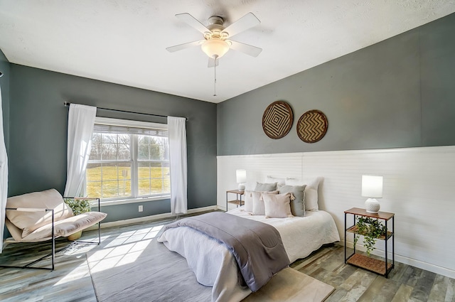 bedroom featuring a ceiling fan, baseboards, and wood finished floors