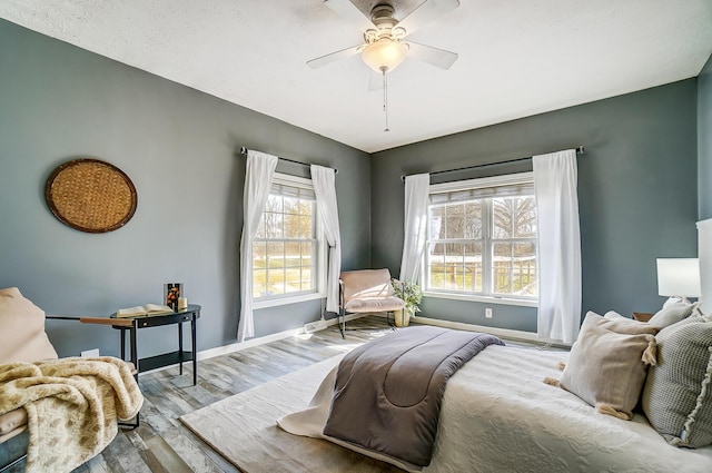 bedroom featuring ceiling fan, baseboards, and wood finished floors