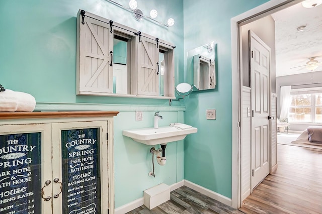 bathroom with a sink, a ceiling fan, baseboards, and wood finished floors