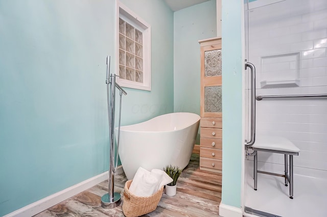 bathroom with a freestanding tub, a shower stall, baseboards, and wood finished floors