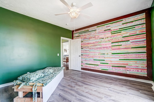 bedroom featuring wood finished floors, a ceiling fan, and baseboards