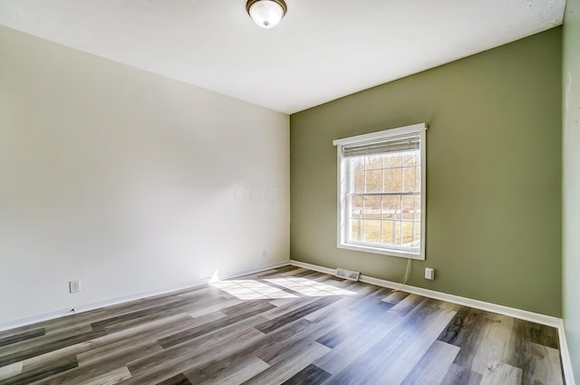 unfurnished room with wood finished floors, visible vents, and baseboards