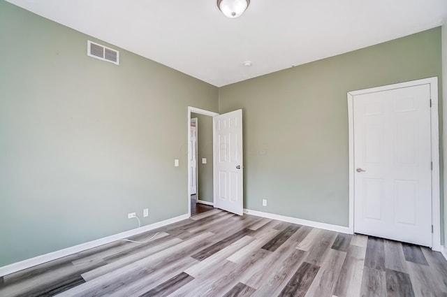 unfurnished room featuring visible vents, baseboards, and wood finished floors