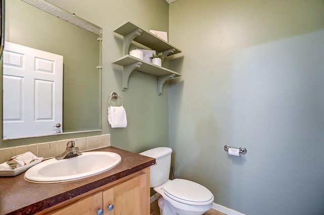 bathroom with vanity, toilet, and baseboards