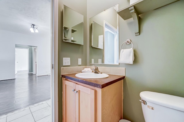 half bathroom featuring tile patterned flooring, vanity, and toilet