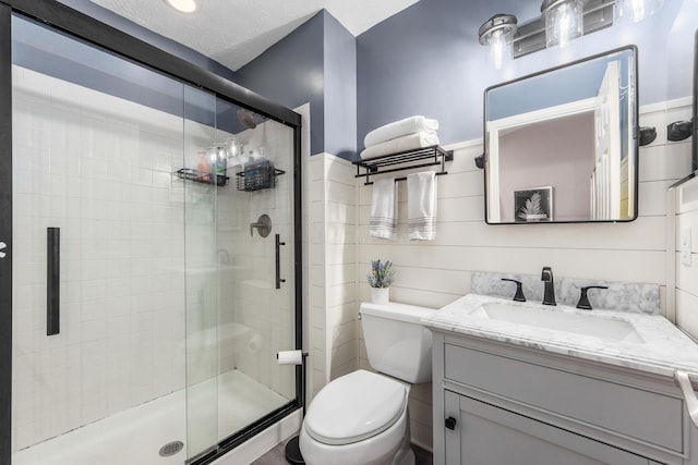 full bath featuring a textured ceiling, a stall shower, vanity, and toilet