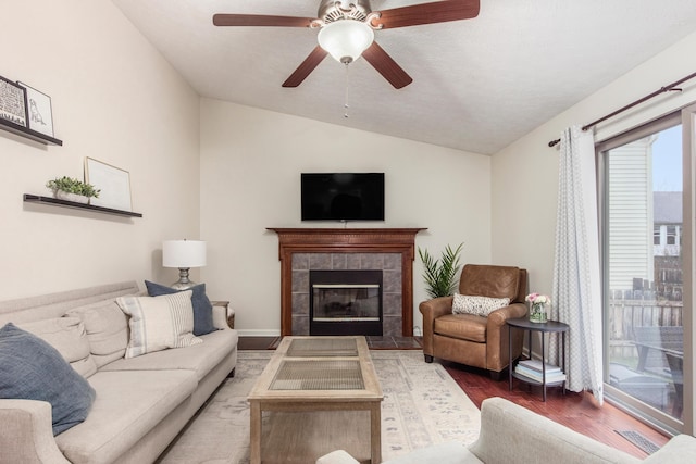 living area with vaulted ceiling, ceiling fan, a fireplace, and wood finished floors