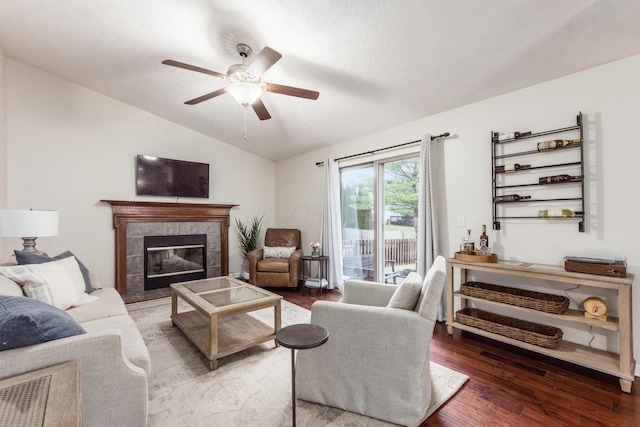 living area featuring lofted ceiling, a fireplace, ceiling fan, and wood finished floors