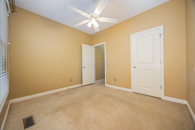 empty room featuring visible vents, baseboards, light colored carpet, and ceiling fan