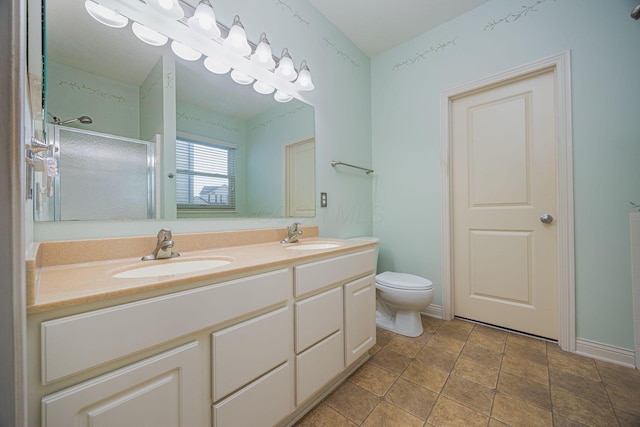 full bath featuring double vanity, a shower with shower door, toilet, and a sink