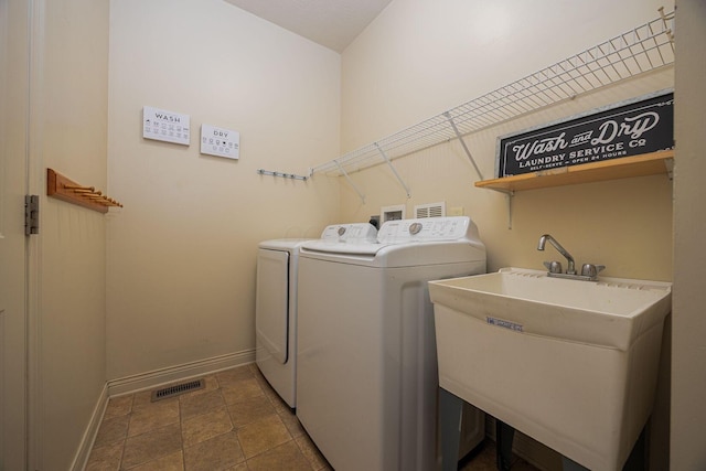 washroom with washing machine and clothes dryer, visible vents, baseboards, laundry area, and a sink