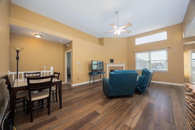 living area with baseboards, dark wood-type flooring, and a ceiling fan