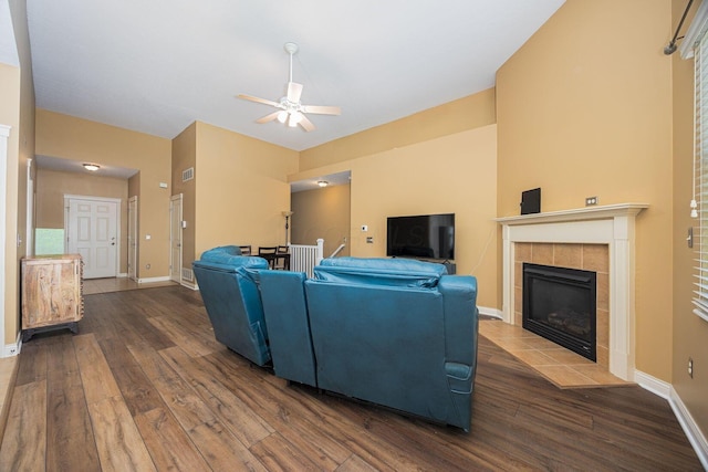 living area with a ceiling fan, wood finished floors, baseboards, and a tile fireplace