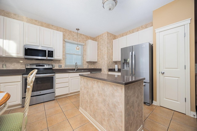 kitchen with a sink, dark countertops, appliances with stainless steel finishes, and light tile patterned floors