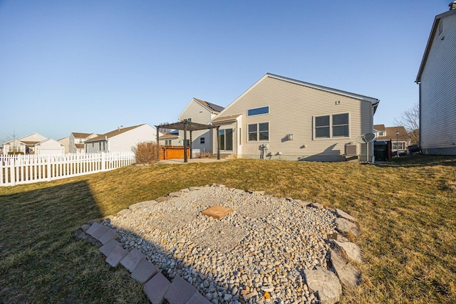 rear view of house featuring a lawn and fence