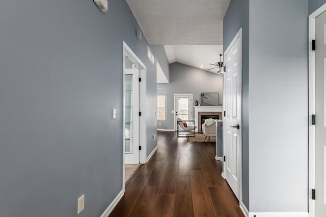 hallway with baseboards, vaulted ceiling, and wood finished floors