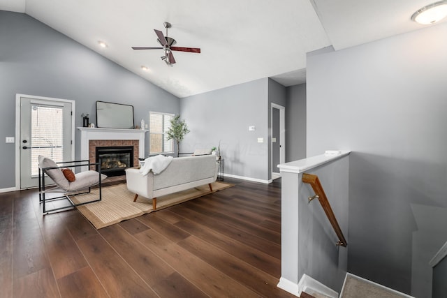 living area featuring ceiling fan, dark wood-type flooring, a fireplace, and baseboards