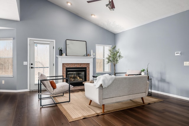 living area featuring ceiling fan, wood finished floors, a tile fireplace, and baseboards