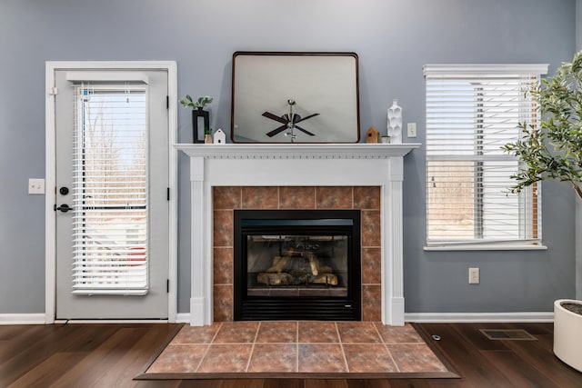 living area featuring plenty of natural light, visible vents, wood finished floors, and a tile fireplace