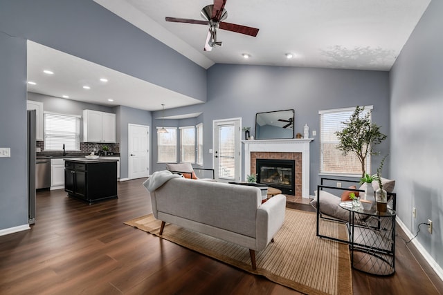 living area featuring dark wood-style floors, vaulted ceiling, a fireplace, and baseboards