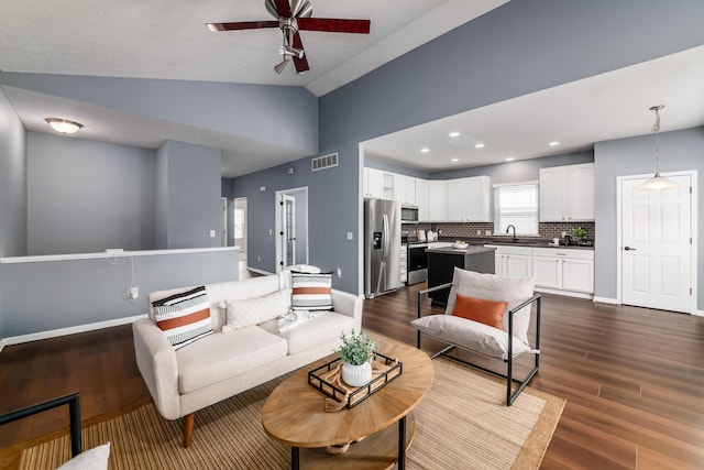 living area featuring lofted ceiling, dark wood-type flooring, and baseboards