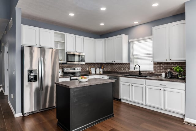 kitchen with dark countertops, dark wood finished floors, stainless steel appliances, and a sink