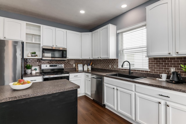 kitchen with dark countertops, appliances with stainless steel finishes, dark wood-type flooring, open shelves, and a sink